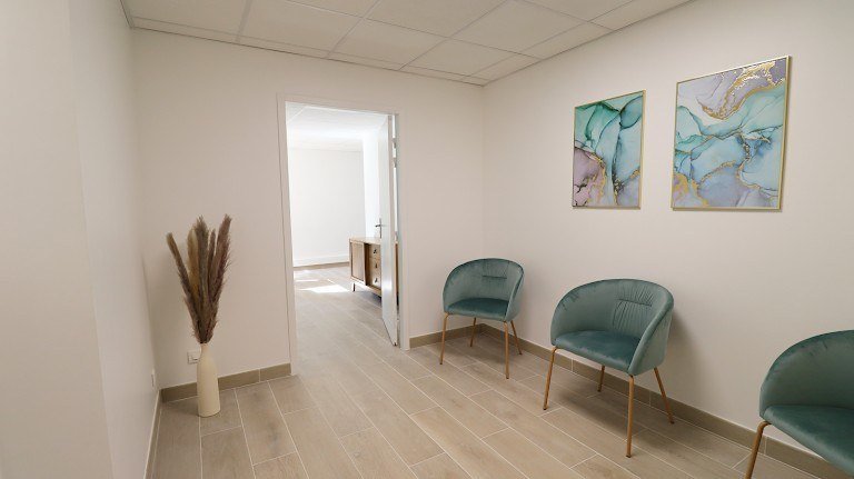 Salle d'attente lumineuse avec fauteuils en velours vert à Champs-sur-Marne.